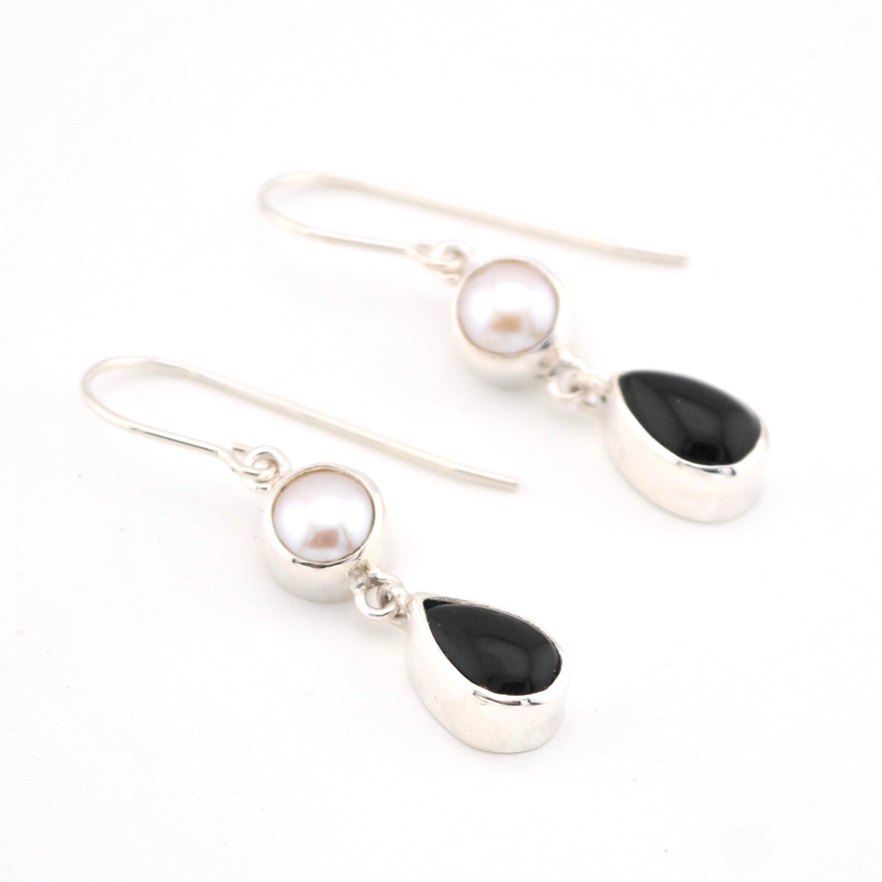 Pair of earrings with pearls and black stones on a white background