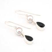Pair of earrings with pearls and black stones on a white background