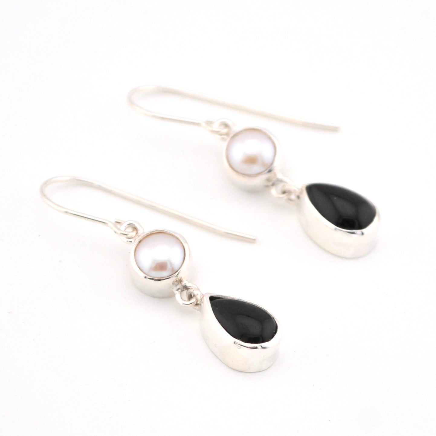 Pair of earrings with pearls and black stones on a white background