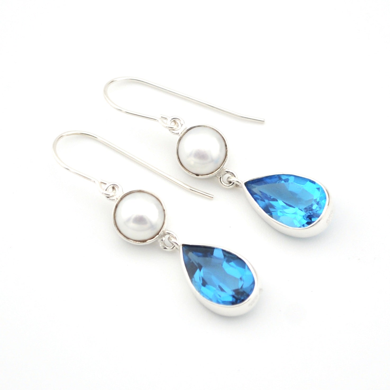 Pair of earrings with pearls and blue teardrop stones on a white background