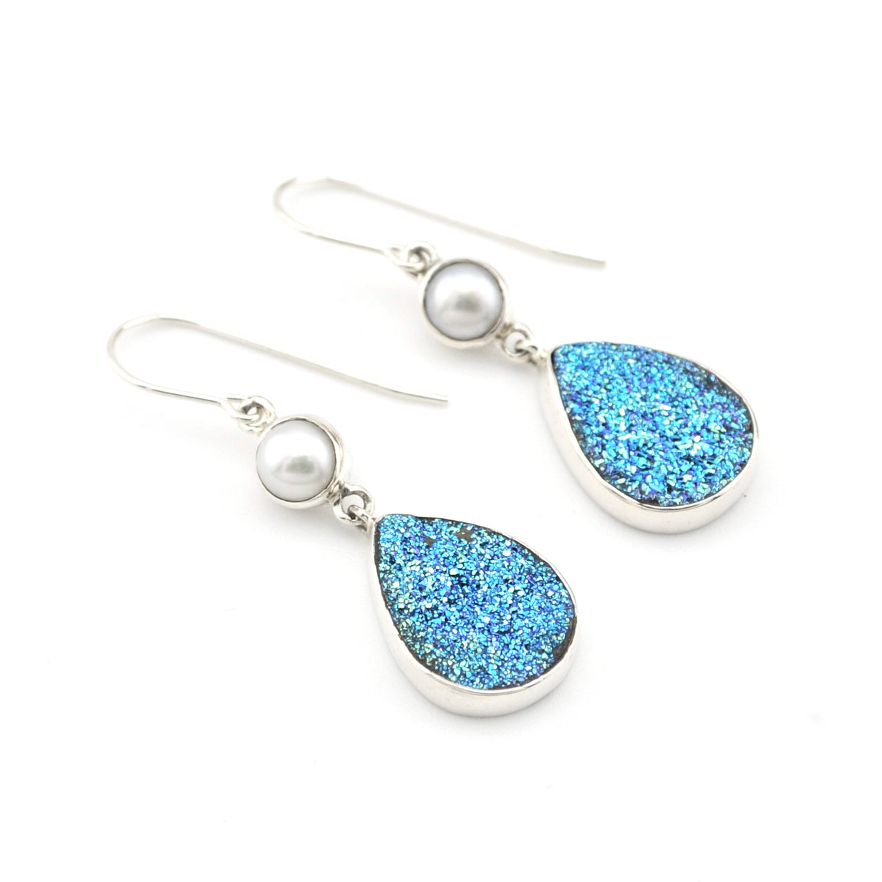 Pair of earrings with blue teardrop-shaped stones and white pearls on a white background