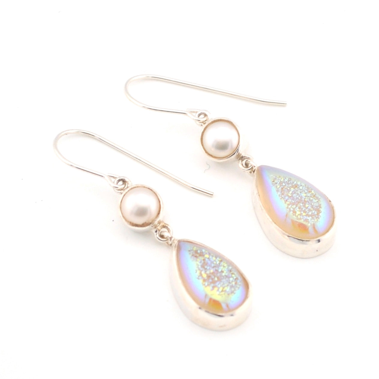 Pair of earrings with teardrop-shaped gemstones and pearls on a white background
