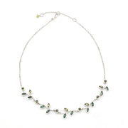Silver necklace with green gemstones on a white background
