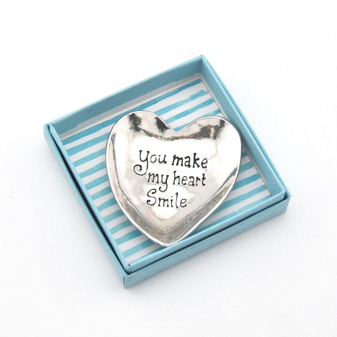 Heart-shaped silver trinket with 'You make my heart smile' text in a striped box