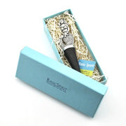A decorative microphone gift set by Basic Spirit, featuring a silver and black microphone nestled in white paper shred inside a light blue gift box, with the matching box lid shown beside it.