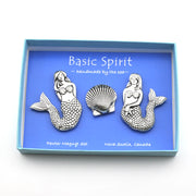 A mermaid-themed pewter magnet set by Basic Spirit, featuring two mermaid figures and a seashell, presented in a light blue box with a blue backing card.