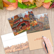 Autumn-themed postcard with a red barn, pumpkins, and leaves on a wooden surface with an envelope and pen.