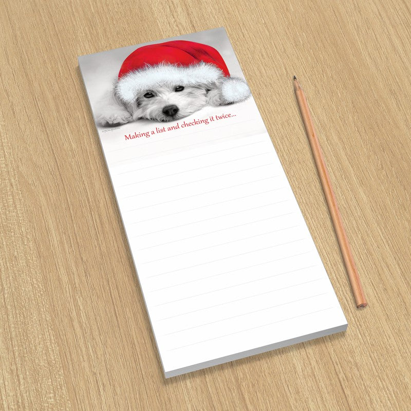 Notepad with a dog wearing a Santa hat on a wooden surface with a pencil.