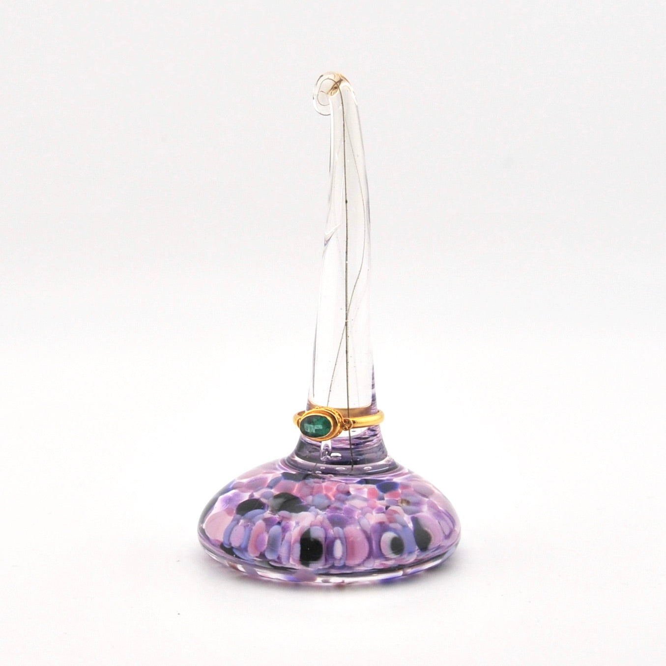Purple glass ring holder with a ring on a white background
