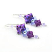 Pair of earrings with purple and blue square beads on a white background