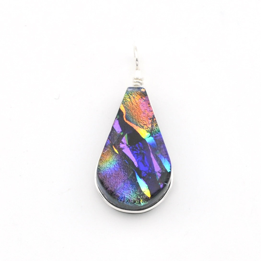 A teardrop-shaped pendant featuring an iridescent, rainbow-colored dichroic glass set in a silver bezel and wavy silver wire top, shown on a plain white background.