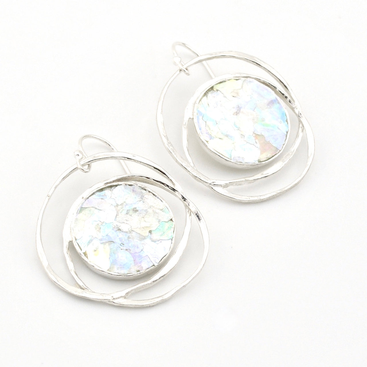 Silver hoop earrings with round, iridescent glass on a white background