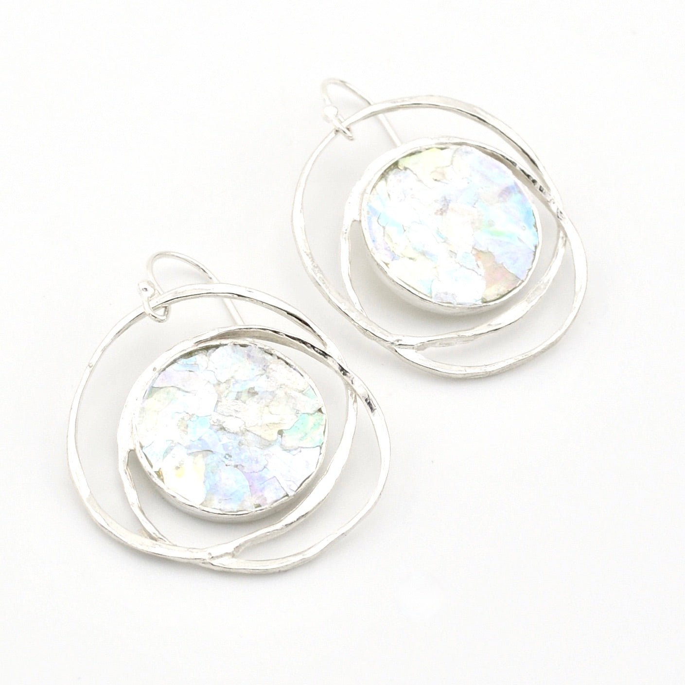 Silver hoop earrings with round, iridescent glass on a white background