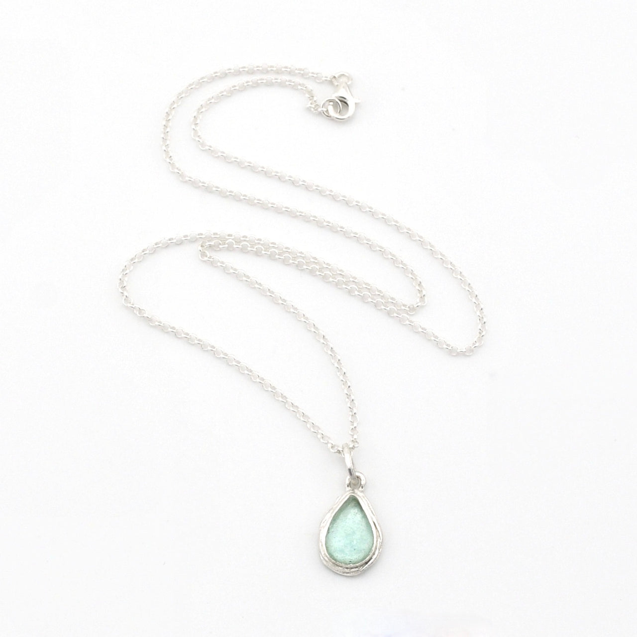 Silver necklace with teardrop Roman glass pendant on white background.