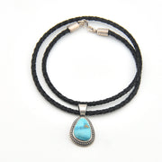 Black braided cord necklace with a turquoise stone pendant on a white background