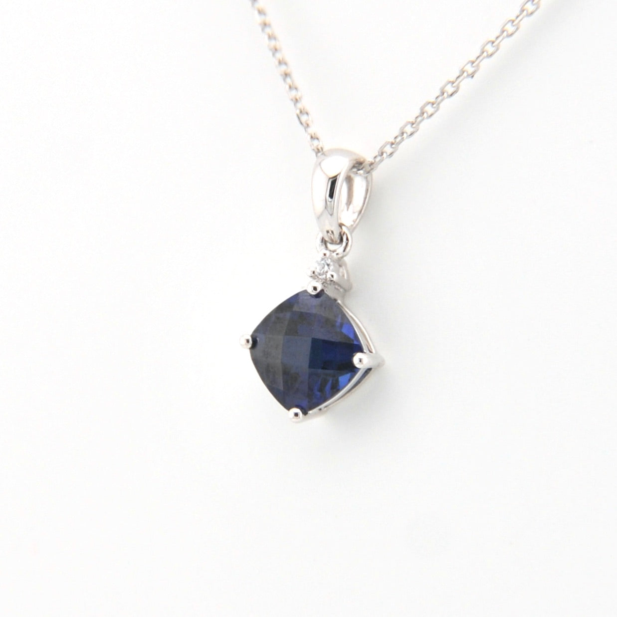 Silver necklace with a blue gemstone pendant on a white background