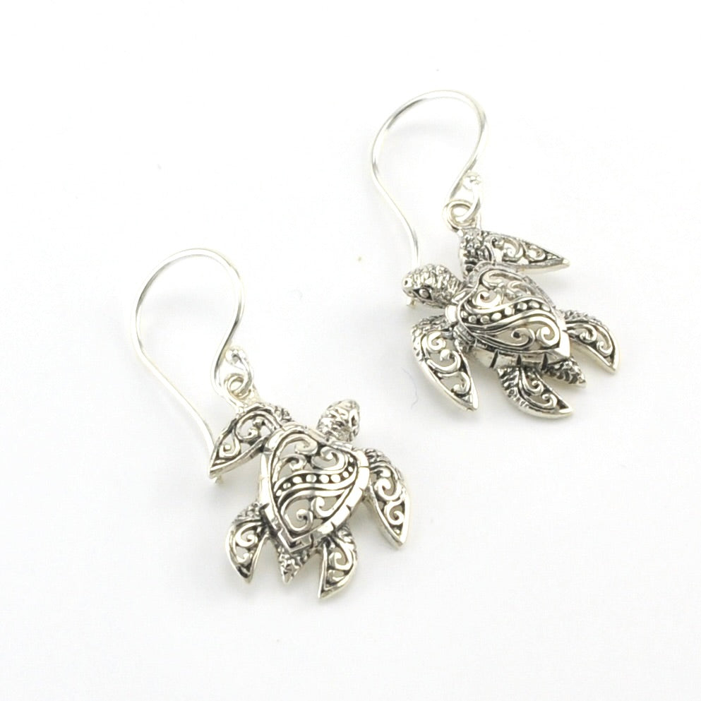 A pair of silver-toned dangle earrings shaped like sea turtles with ornate filigree detailing, shown on a plain white background.