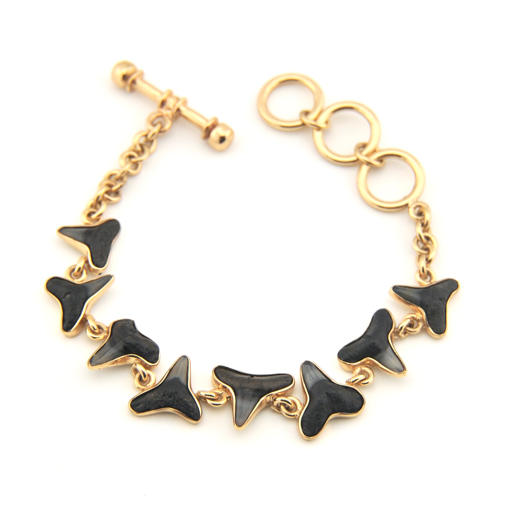 Gold bracelet with black shark tooth charms on a white background