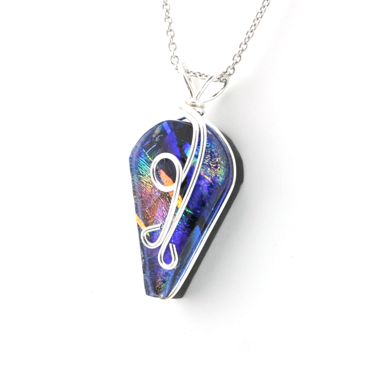 A coffin-shaped pendant necklace featuring a blue iridescent dichroic glass with silver wire detailing, suspended from a silver chain against a white background.