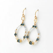 A pair of gold-tone dangle earrings with beaded teardrop-shaped hoops, featuring dark teal, frosted white, and light blue beads on a clean white background.