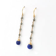A pair of gold drop earrings with small metallic beads and teardrop-shaped blue lapis lazuli stones, shown on a plain white background.