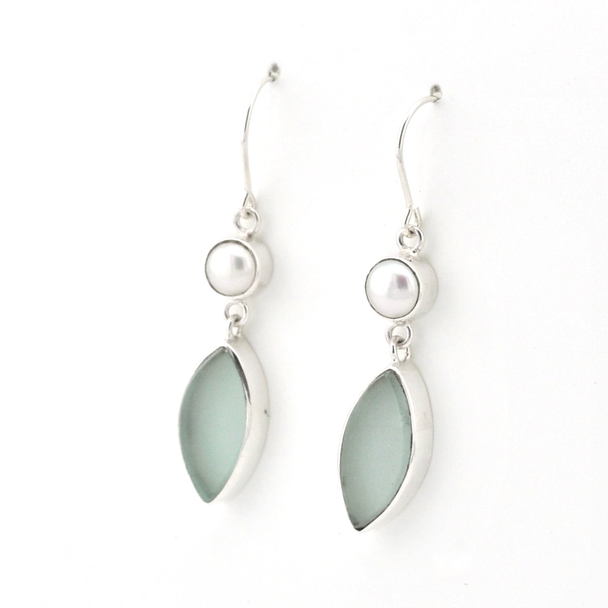 A pair of silver dangle earrings featuring a small white pearl and a larger teardrop-shaped light green stone in a silver bezel setting, shown against a plain white background.