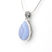 A silver teardrop pendant necklace featuring a light blue marbled stone in a silver bezel with ornate filigree detailing on the sides, suspended from a silver snake chain against a white background.