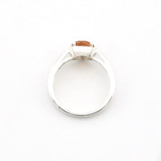 A silver ring with a small rectangular orange gemstone, photographed from above on a plain white background.