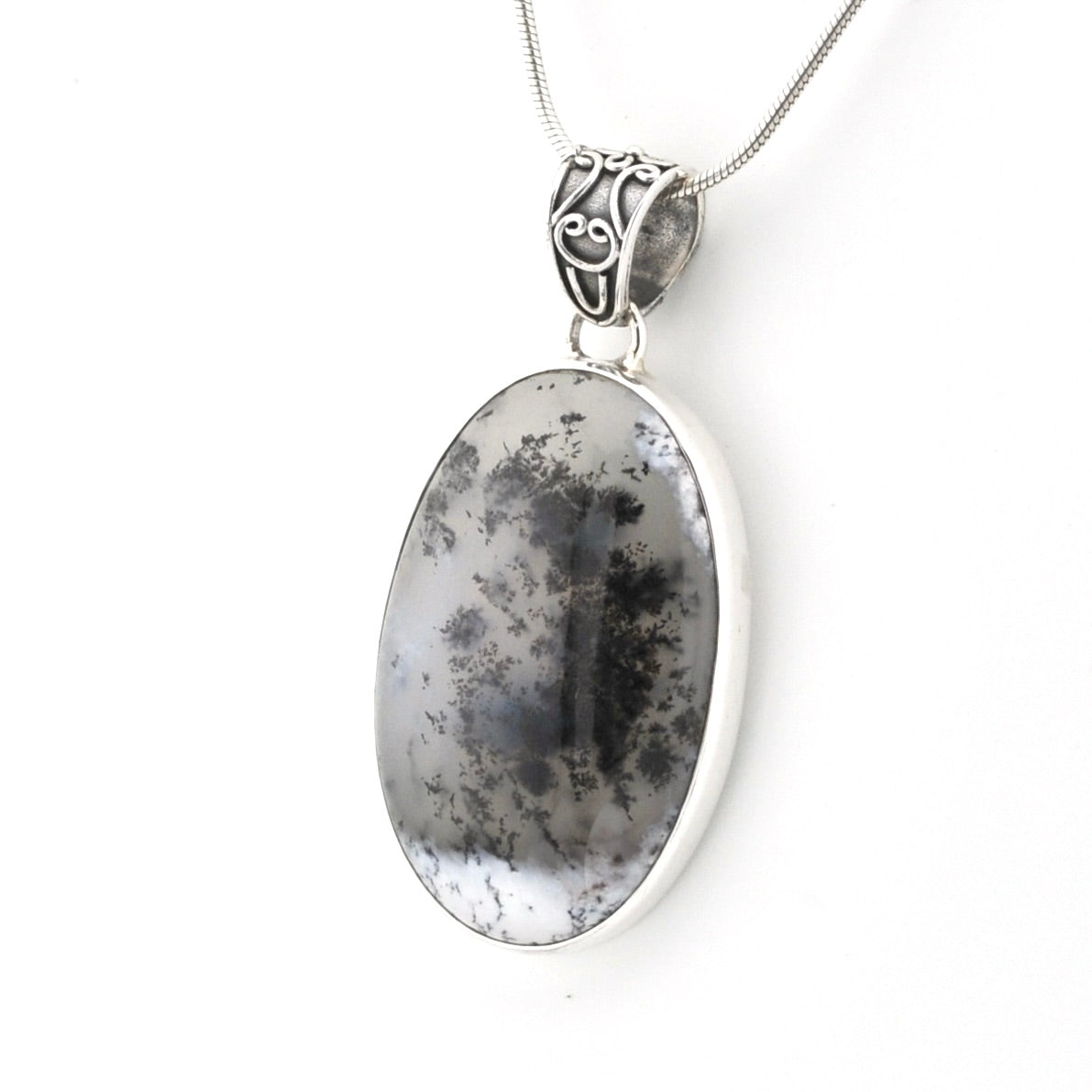 An oval pendant necklace featuring a black and white marbled stone, set in a polished silver bezel with an ornate silver bail, suspended from a silver chain against a white background.