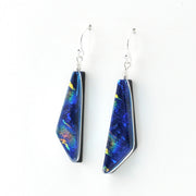 A pair of dangle earrings with irregular blue and iridescent dichroic glass pendants on silver fishhook wires, shown against a plain white background.