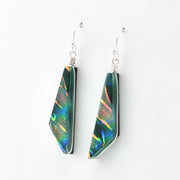 A pair of geometric dangle earrings featuring iridescent green and blue dichroic glass set in silver, shown against a plain white background.