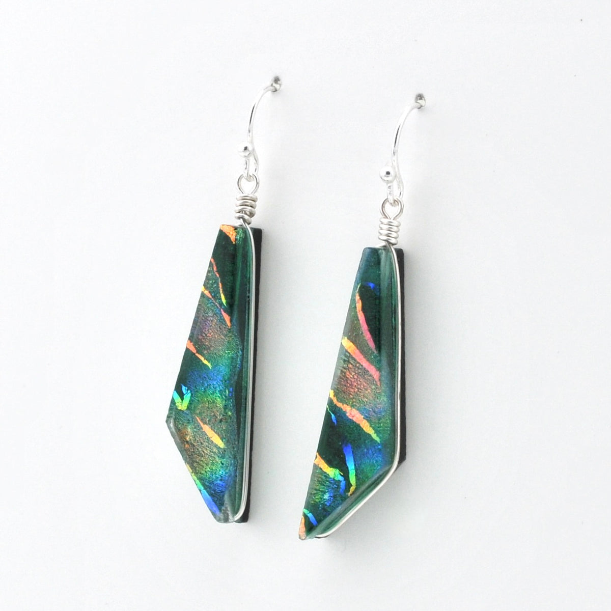 A pair of geometric dangle earrings featuring iridescent green and blue dichroic glass set in silver, shown against a plain white background.