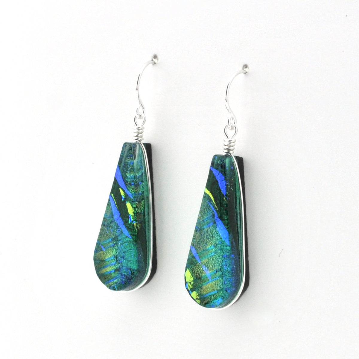 A pair of teardrop-shaped drop earrings with iridescent green and blue dichroic glass on silver fishhook wires, shown against a plain white background.