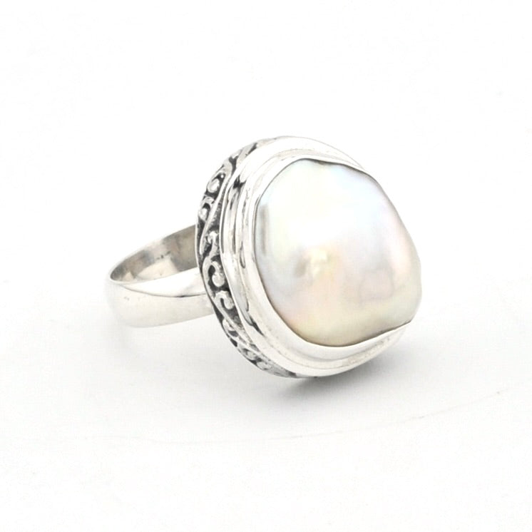 A sterling silver ring featuring a large, irregular-shaped white pearl with iridescent sheen, set in an ornate silver bezel on a plain white background.