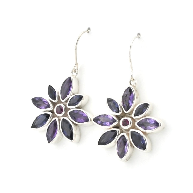 A pair of silver dangle earrings featuring a flower design with marquise-cut purple gemstones and a small round purple center stone, shown on a plain white background.