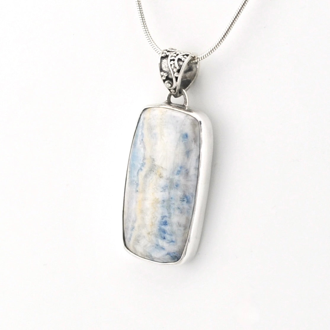 A silver-toned rectangular pendant necklace featuring a polished light blue and white marbled stone, suspended from a delicate silver chain against a plain white background.