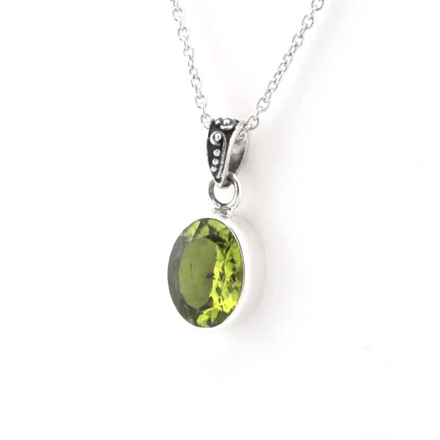 An oval green gemstone pendant necklace set in a silver bezel with a silver chain, shown against a plain white background.