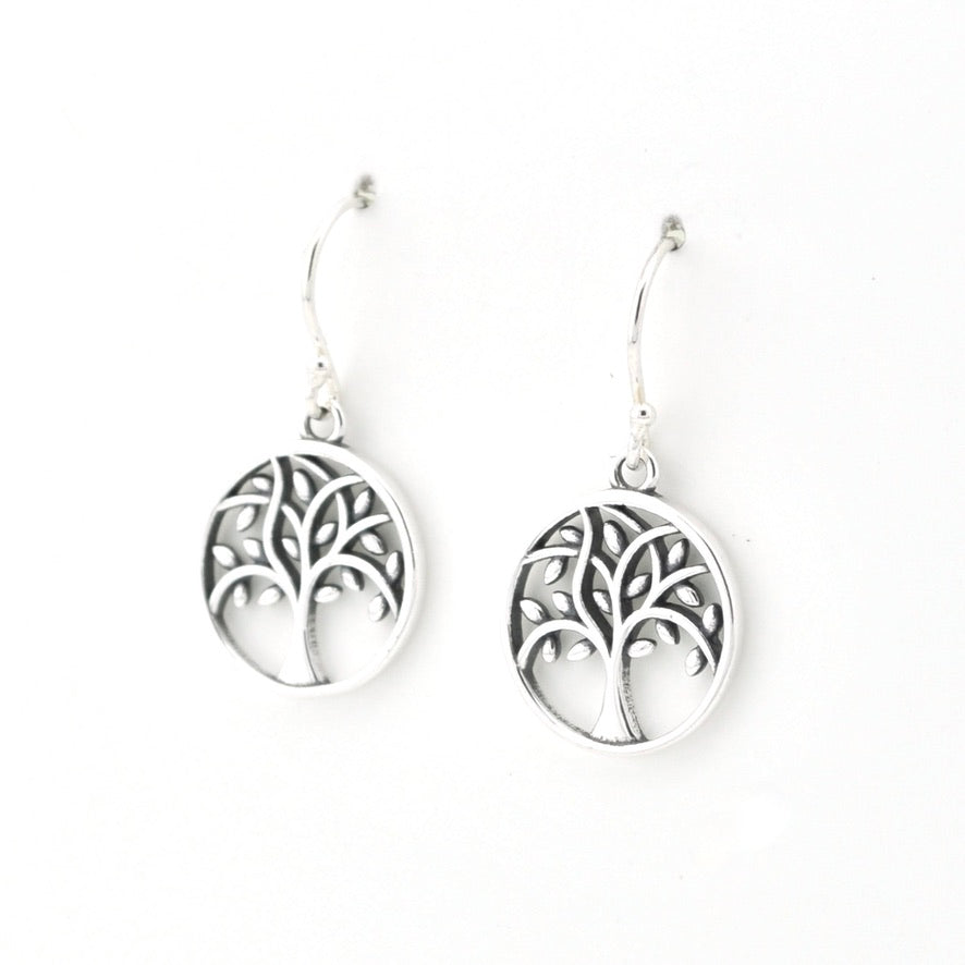 A pair of silver tree of life dangle earrings with circular cutout charms and fishhook wires, shown on a plain white background.