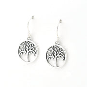 A pair of silver tree of life dangle earrings with circular cutout charms and fishhook wires, shown on a plain white background.