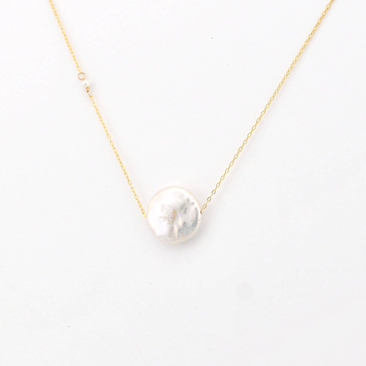 Pearl necklace on a gold chain against a white background