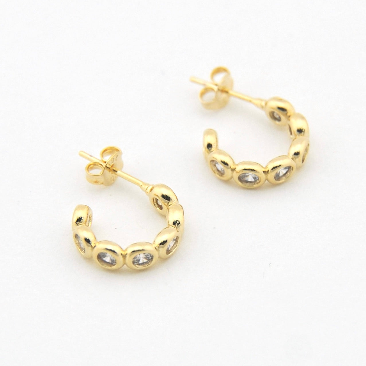 Gold hoop earrings with embedded stones on a white background