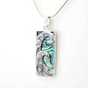 Silver pendant with wave design and abalone shell inlay on a white background