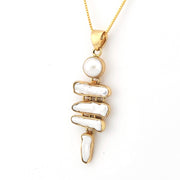 Gold necklace with a pendant featuring stacked white stones on a white background