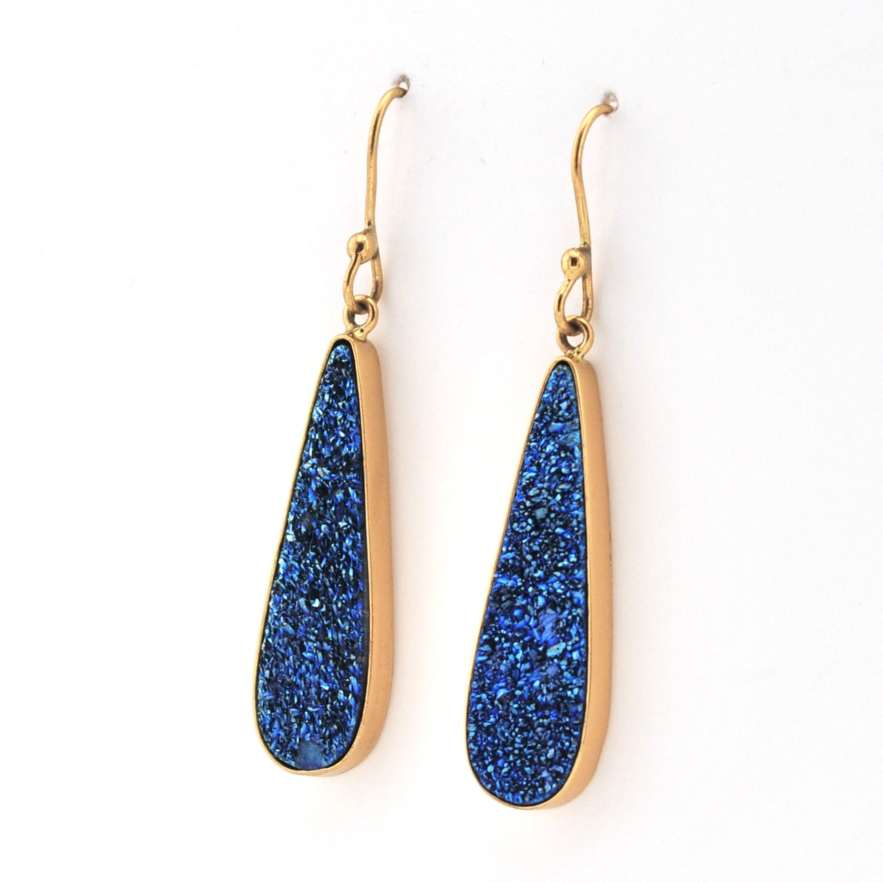 Gold earrings with blue stone drops on a white background