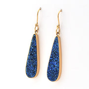 Gold earrings with blue stone drops on a white background
