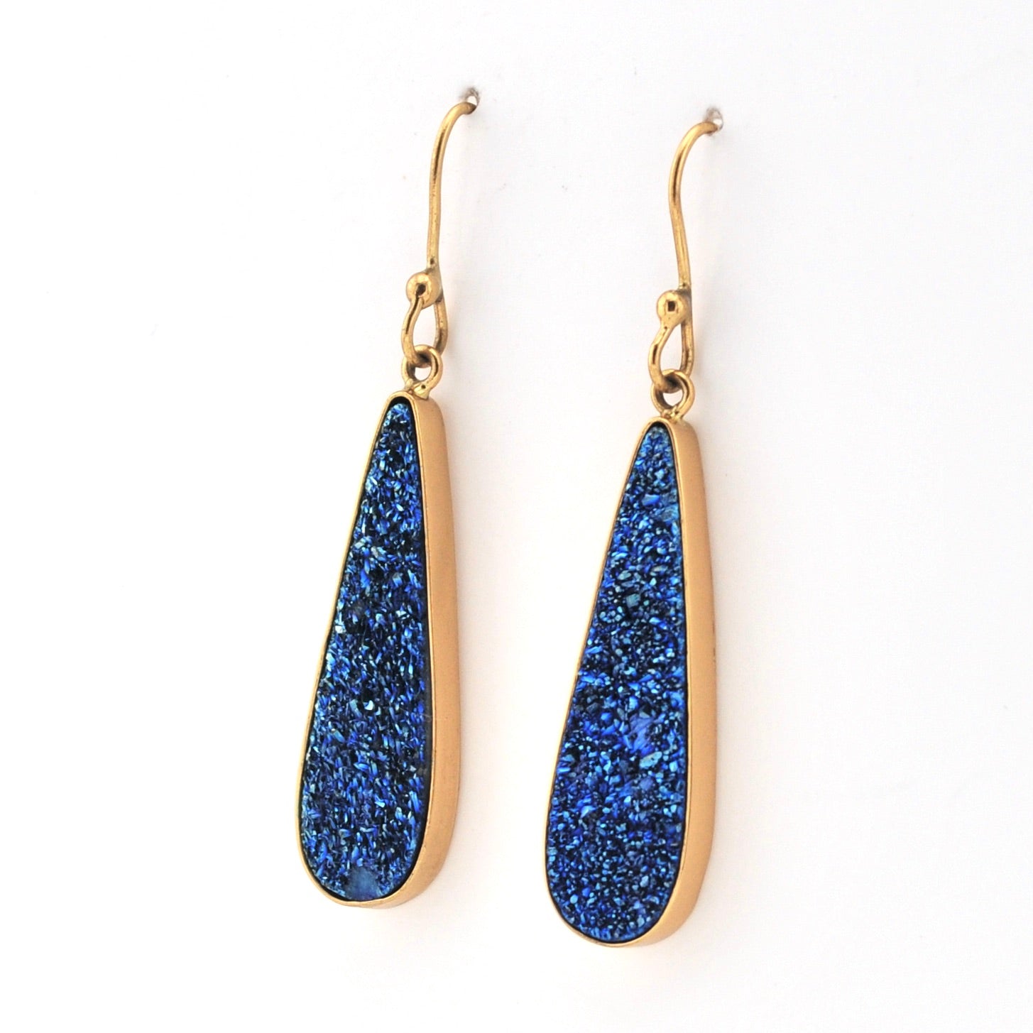 Gold earrings with blue stone drops on a white background