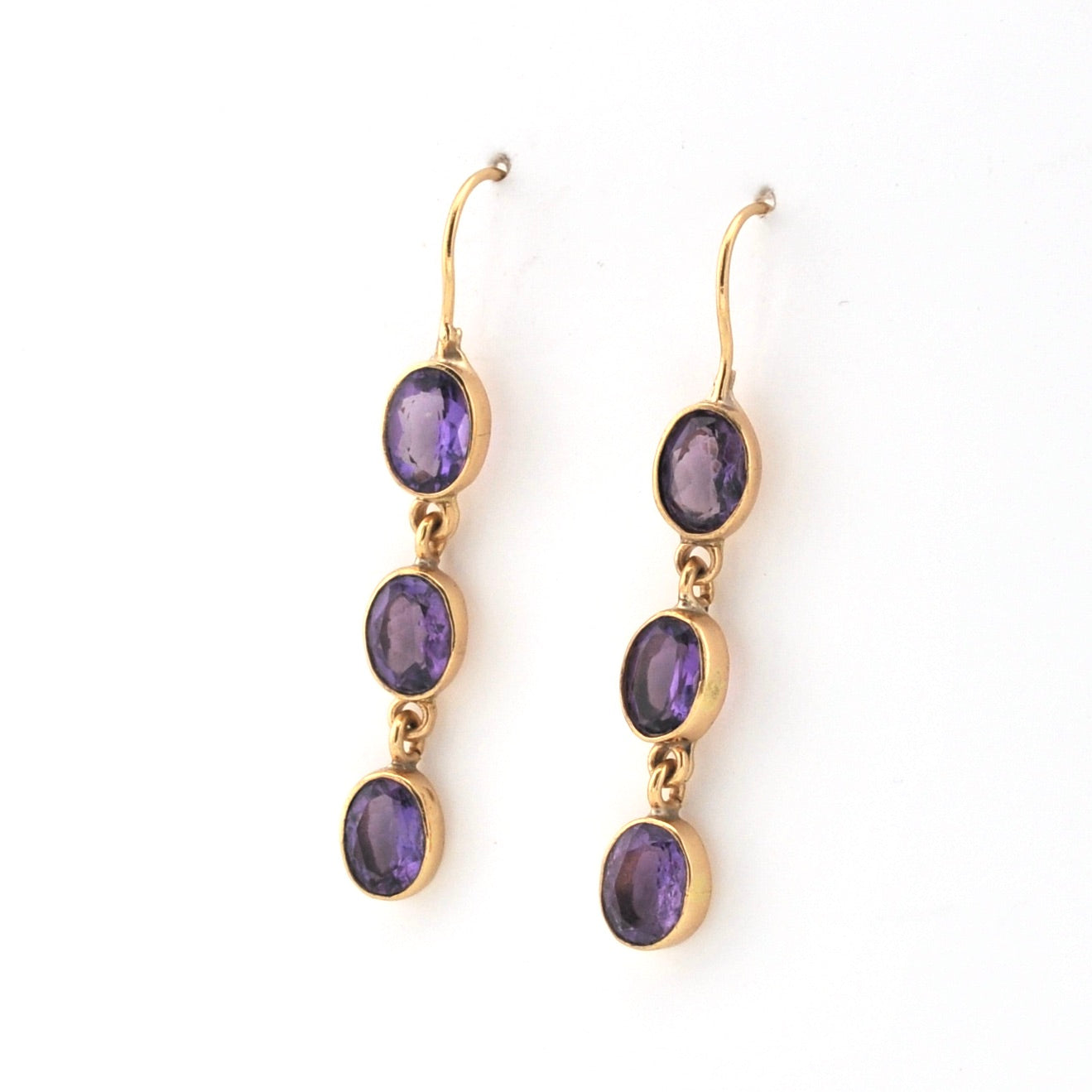 Gold earrings with purple gemstones on a white background