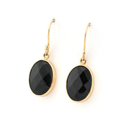 Gold earrings with black oval stones on a white background