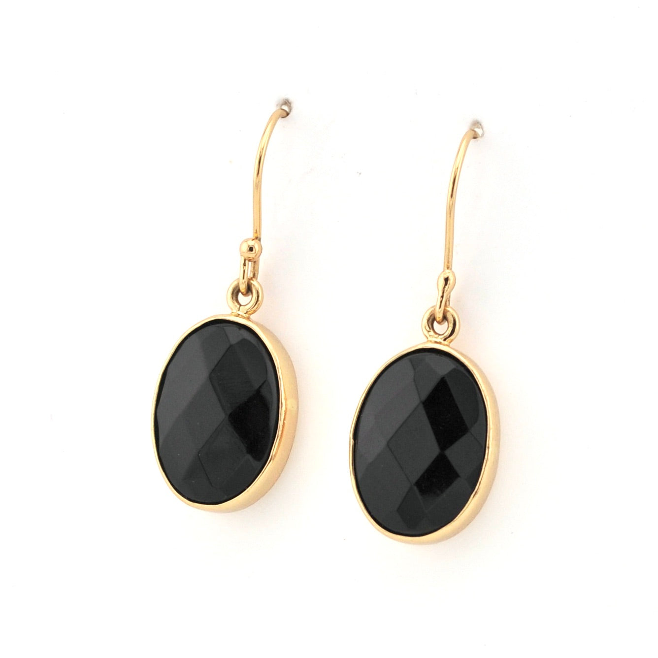 Gold earrings with black oval stones on a white background