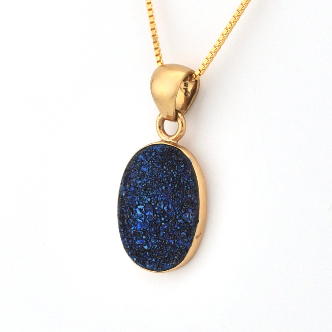 Gold necklace with a blue pendant on a white background